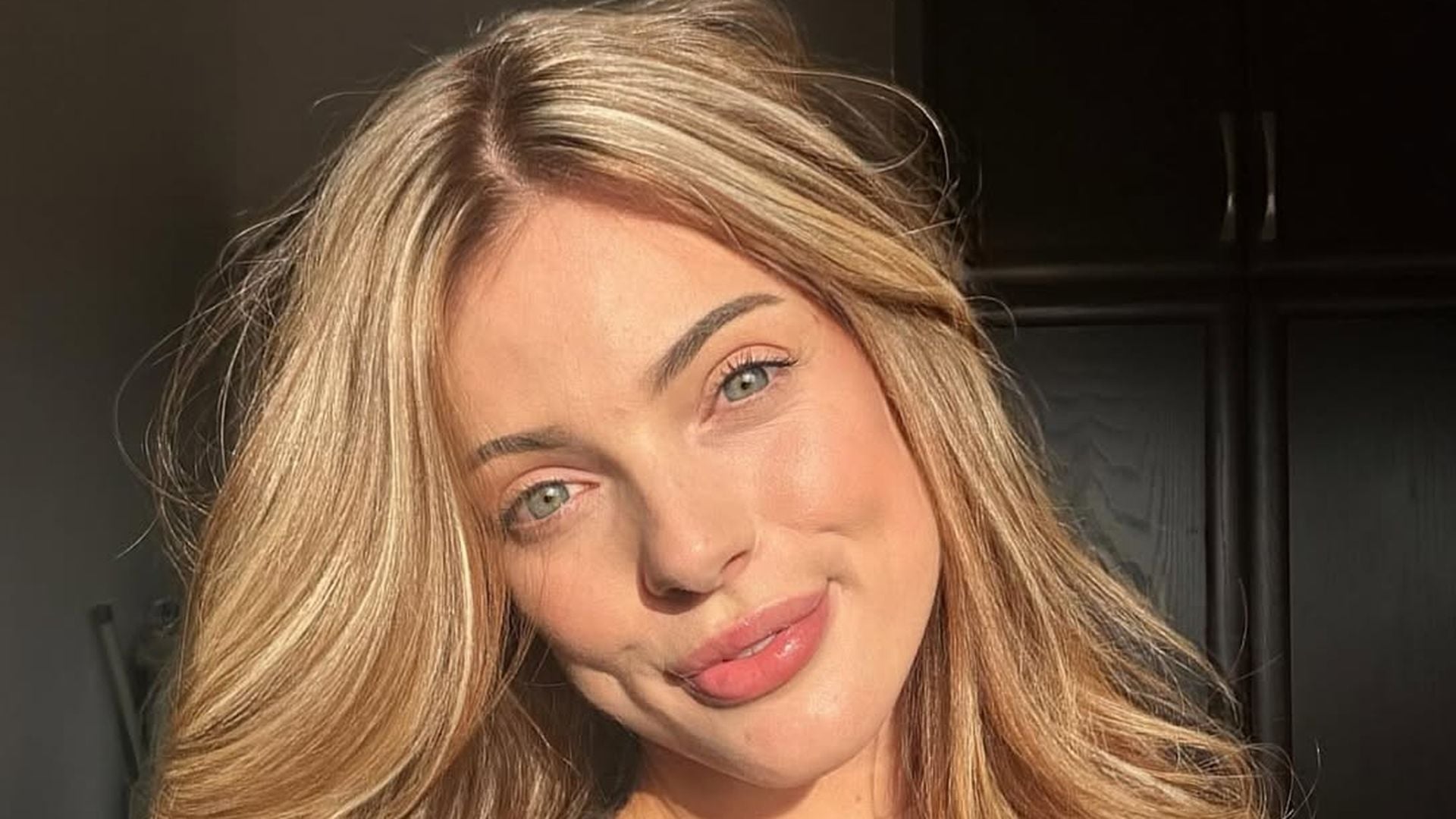 Olivia Laurea und Ashkan Saberian lächeln glücklich in die Kamera, während sie sich vor einer traumhaften Kulisse mit Meer und Blumenbogen auf Zypern umarmen.