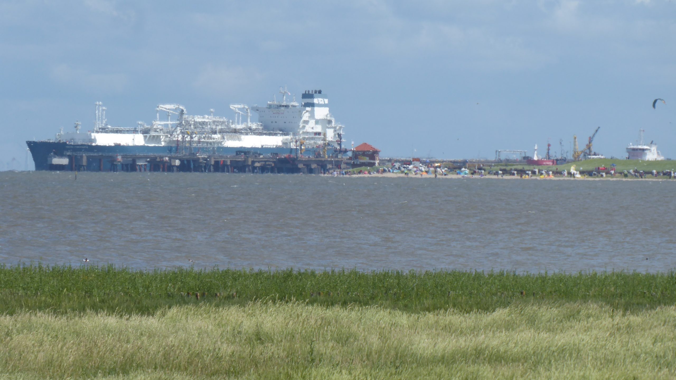 Ein großer LNG-Tanker liegt vor Anker, während kleinere Schiffe im Hintergrund zu sehen sind, was die Bedeutung des Flüssigerdgas-Transports unterstreicht.