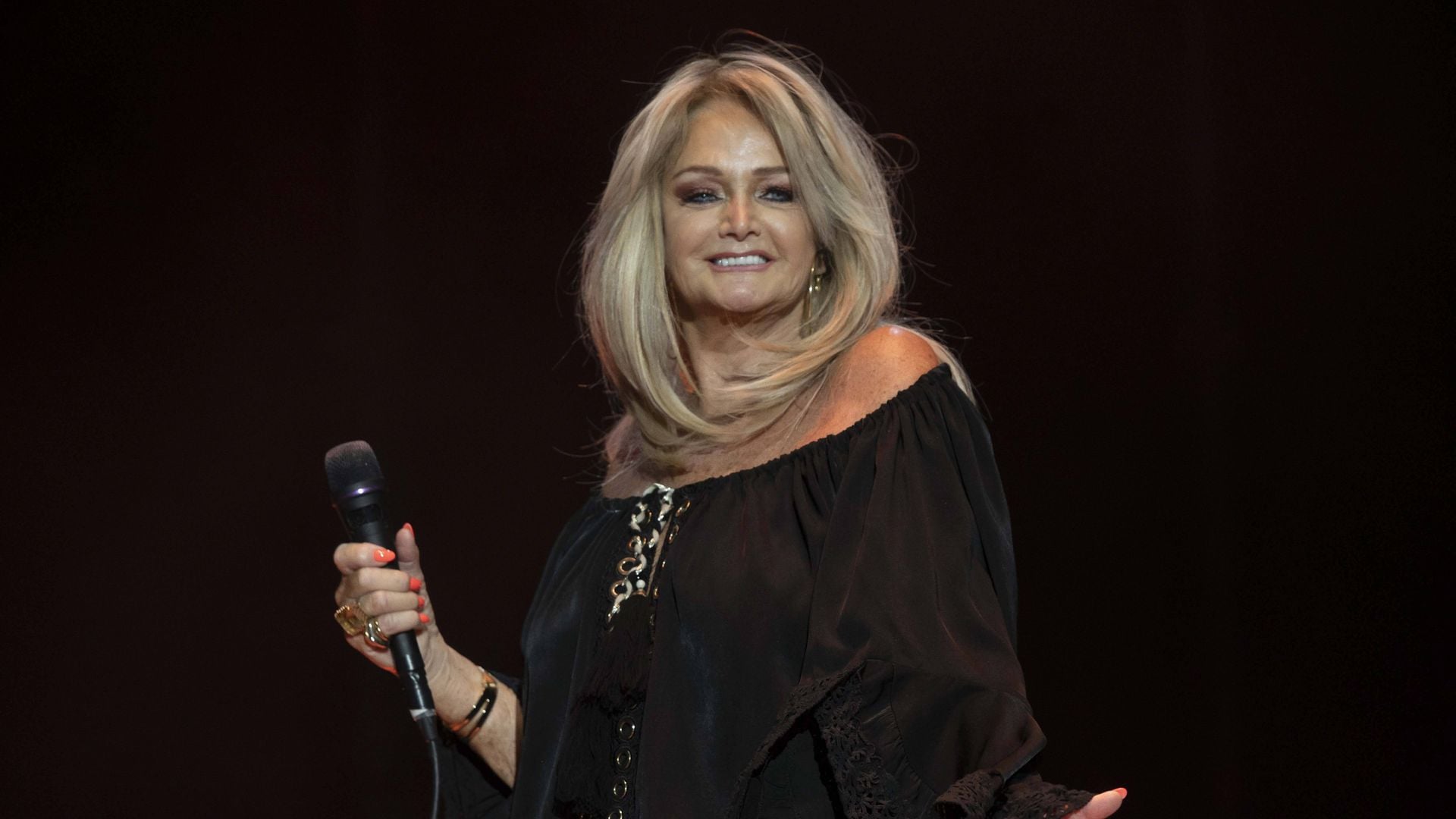 Bonnie Tyler singt auf einer Bühne, ihr Gesicht ist im Profil zu sehen.