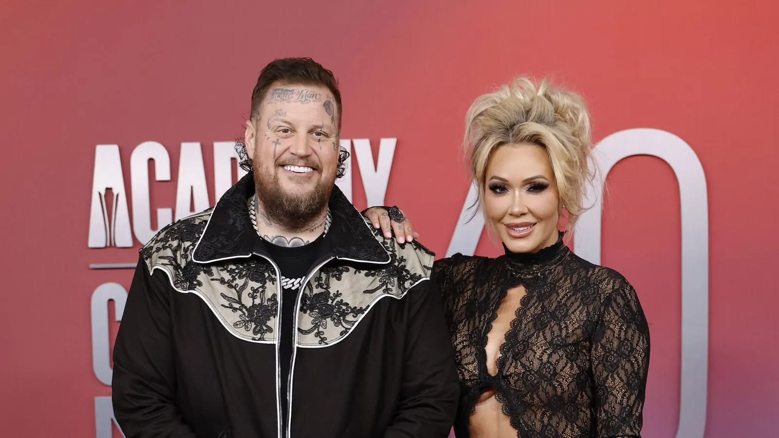 Jelly Roll und seine Frau Bunnie Xo posieren gemeinsam für ein Foto auf einem roten Teppich.