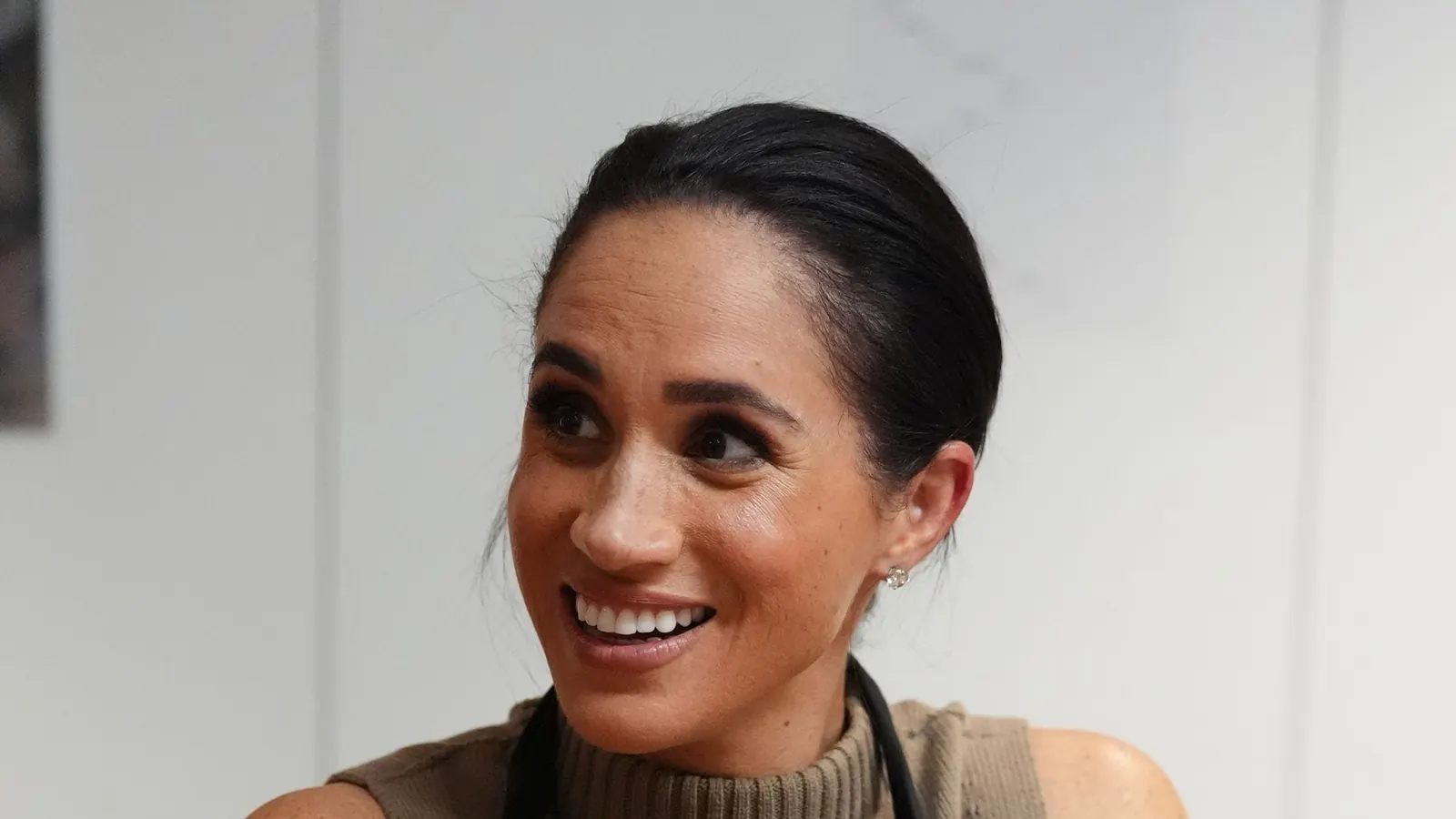 Prinz Harry und Herzogin Meghan bei einem royalen Termin, beide lächelnd in die Kamera blickend