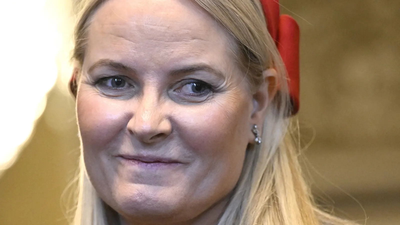 Kronprinzessin Mette-Marit und Kronprinz Haakon auf einer Couch mit Fanschals, die ein Fußballspiel verfolgen.