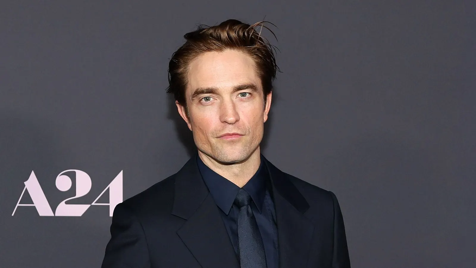 Robert Pattinson als Batman im Regen, während das Logo des Films erscheint.